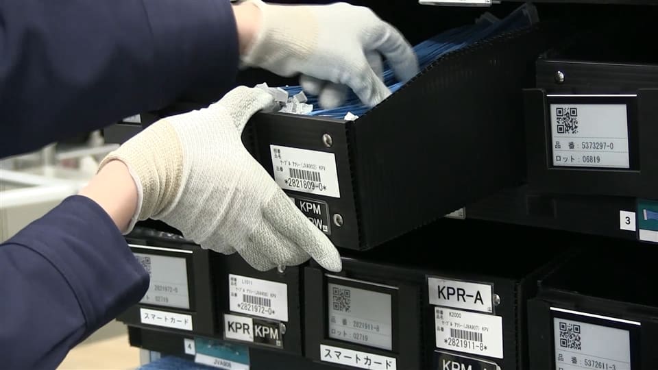 A person in white gloves is putting something into a box.