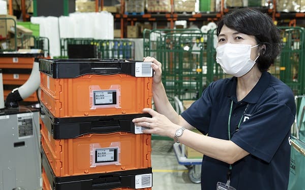 A woman in a warehouse with boxes and a mask.